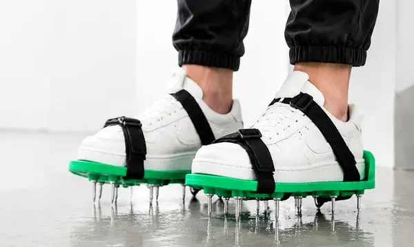 green spike sandals strapped on white sneakers on wet floor