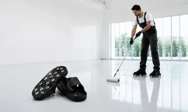 black spike sandals and worker applying floor with roller